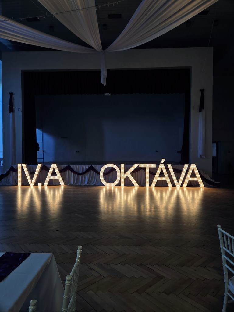 Svietiaci nápis OKTÁVA a IV.A (s bodkou) na stužkovej na Gymnáziu v Šamoríne.